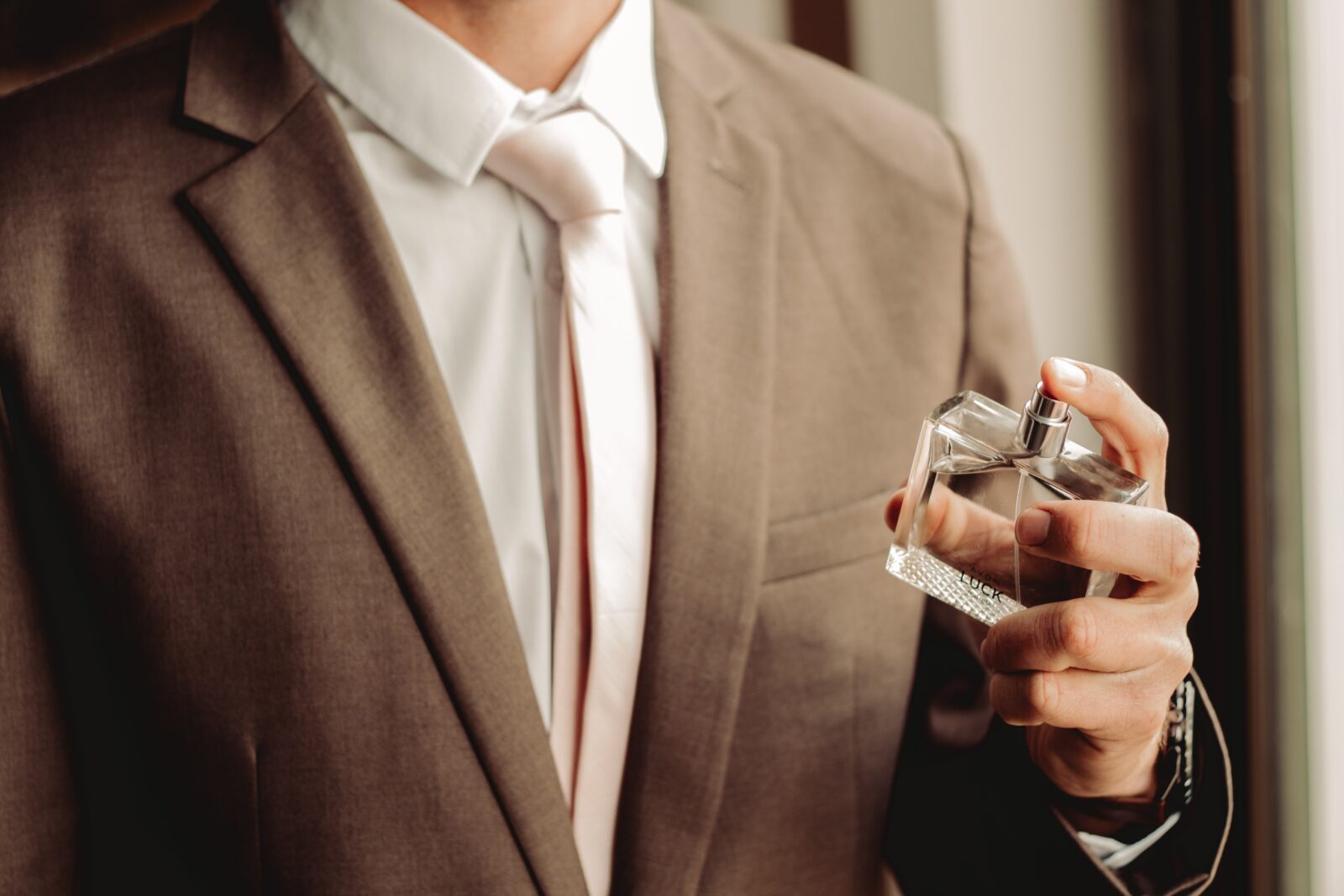 Man in suit with glass bottle of aftershave