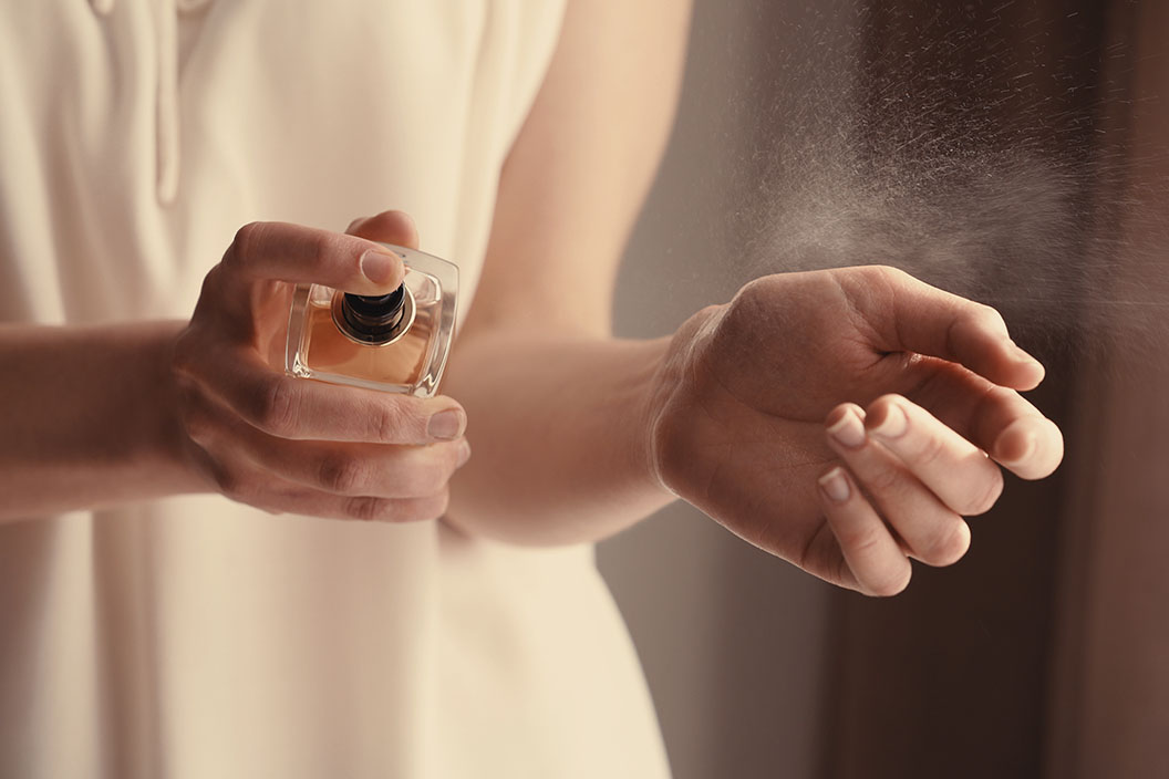 Lady spraying perfume on wrist