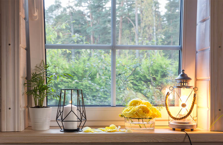 Candles, flowers and lanterns on window sill