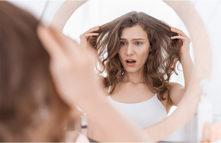 woman pulling hair in mirror